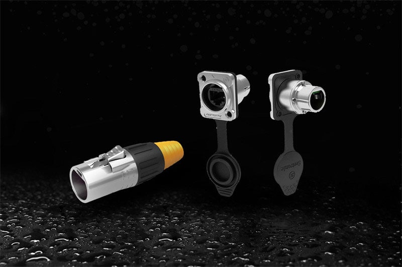 Three connectors on a wet black surface: one with a yellow cap, two with black caps.