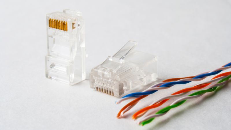 Two RJ-45 connectors beside four twisted Ethernet wire pairs on a white background.